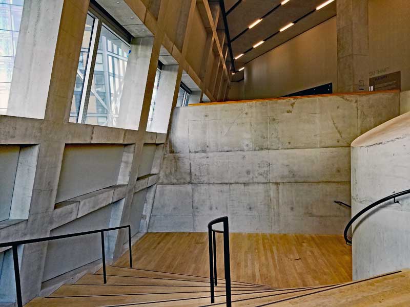The nice sweeping lines of the staircase in contrast to the angular elements in the structure. Also note the contrast between the harsher concrete and the warm wood flooring.