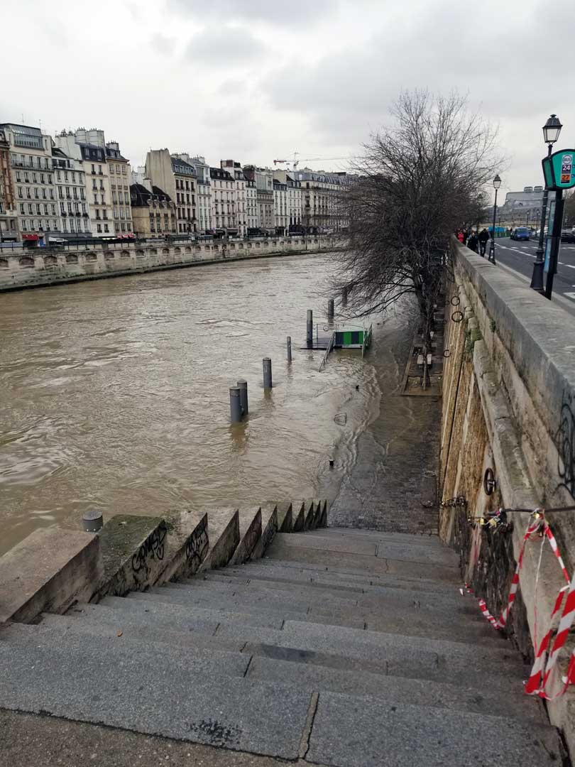 Flooded stairs leading down to a walkway by the Seine.