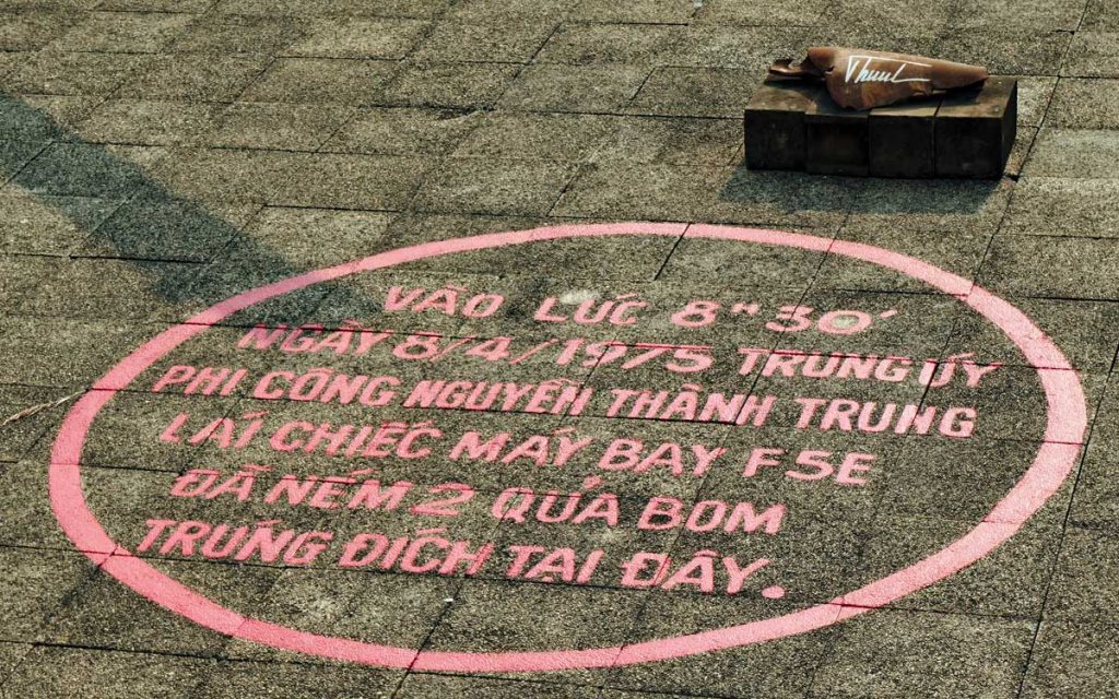A piece from the April 1975 Palace bombing sits by the marker for where one bomb hit the helipad. It has been signed by the renegade pilot Nguyễn Thanh Trung.
